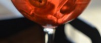 Aperol Spritz drink, served in a class bright red color iced and orange slices